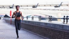 How to run a faster 5k: Pictured here, an athlete jogging along the banks of the River Thames early in the morning, while listening to music on her smartphone or music player