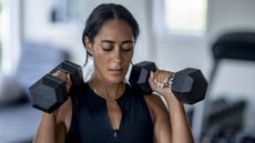 Woman in gym holding dumbbells by shoulders