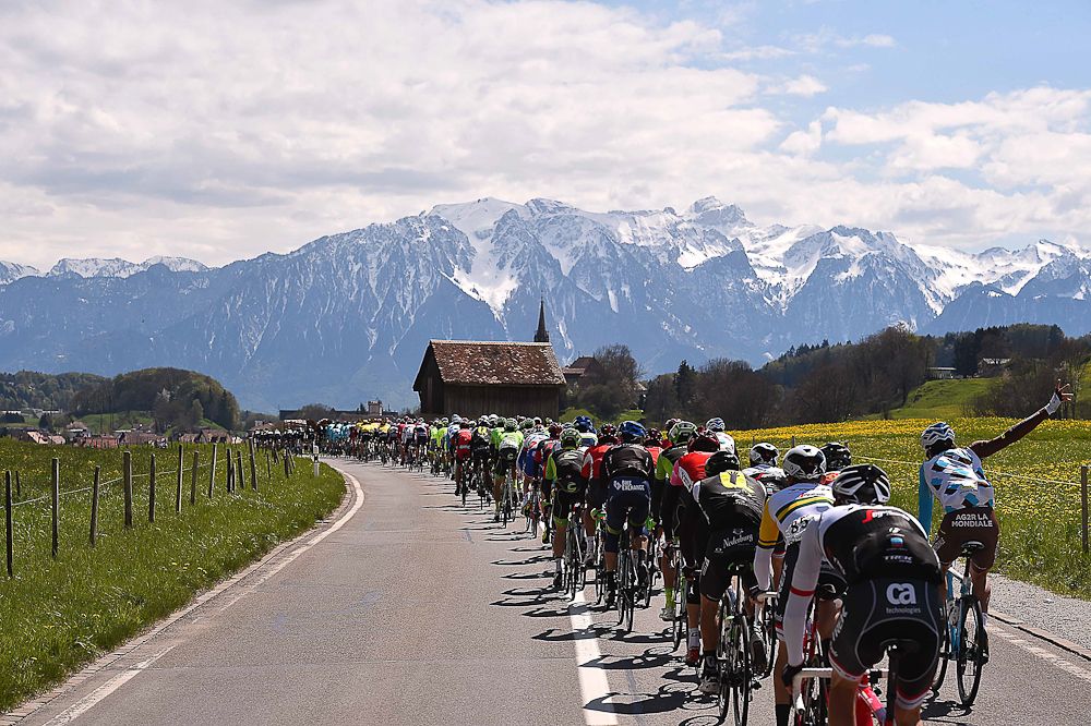 Mountains rise in the background as the peloton makes its way to the finish of stage 4 at the Tour de Romandie.