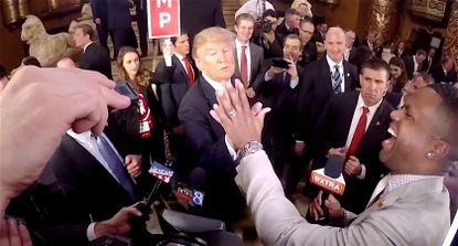 Donald Trump compares hands with an entertainment reporter