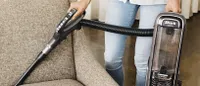 The Shark Apex DuoClean with Zero-M Powered Lift-Away in handheld form vacuuming a sofa
