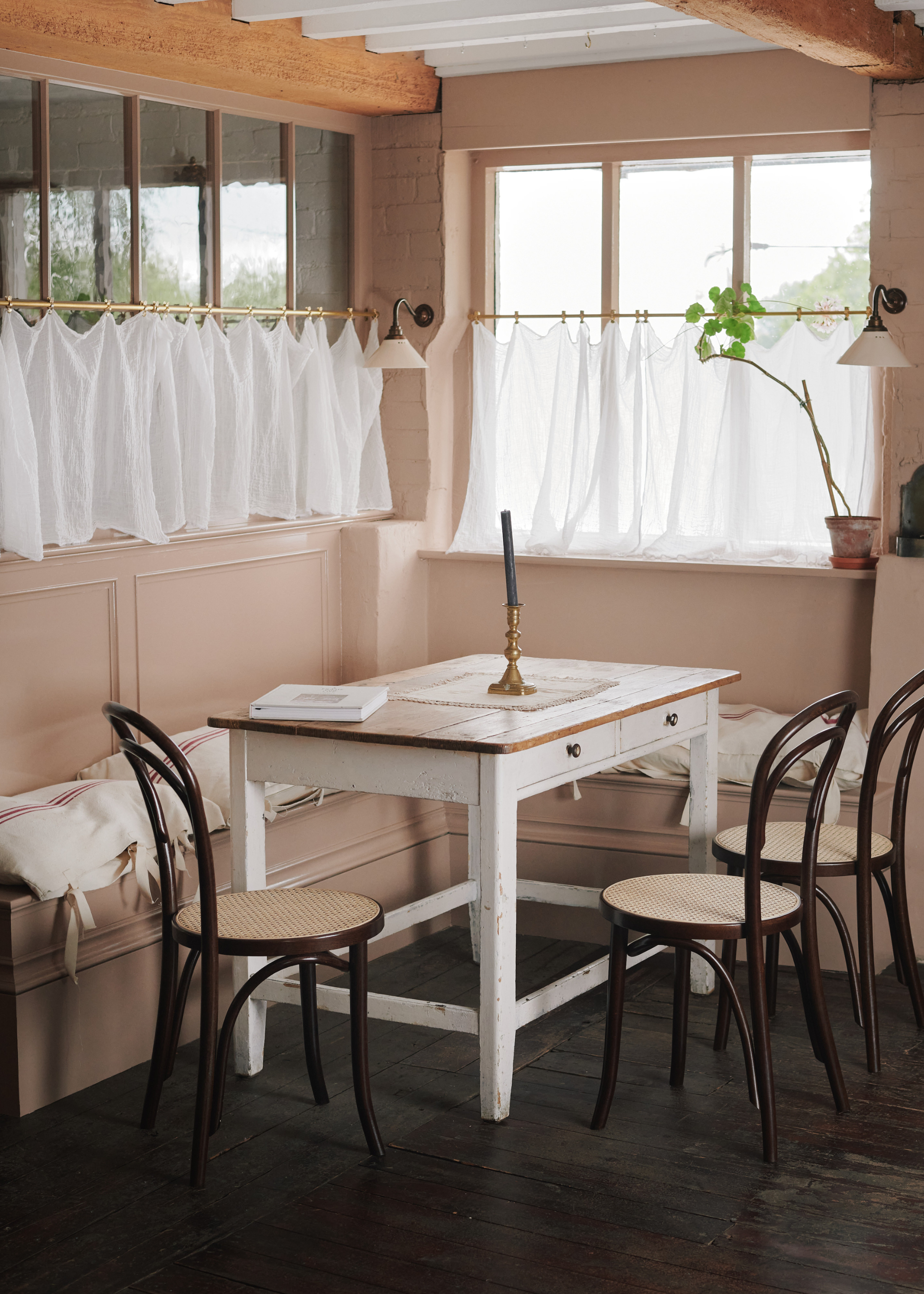 a cozy kitchen corner with bench seating and half curtains around the windows