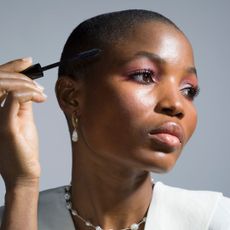 Best lengthening mascara - picture of a black woman with hot pink eyeshadow applying mascara
