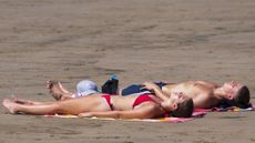 Couple sunbathing on beach in Wales