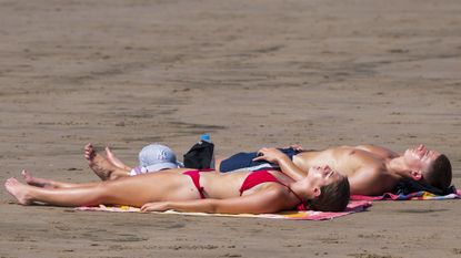 Couple sunbathing on beach in Wales