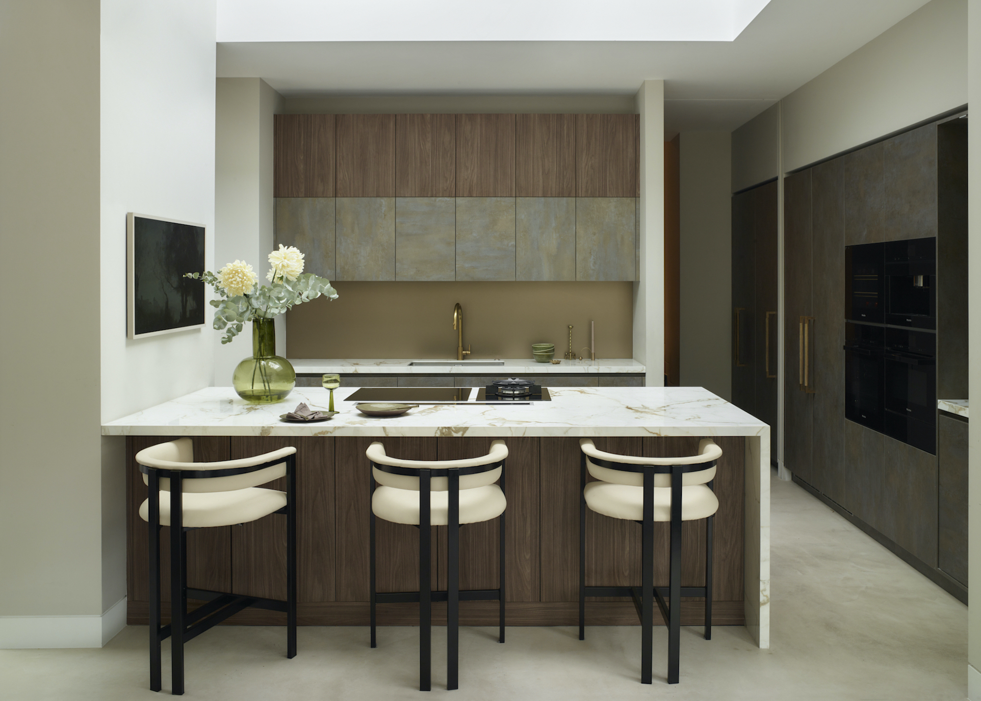 kitchen with dark units and pale worktops and three barstools