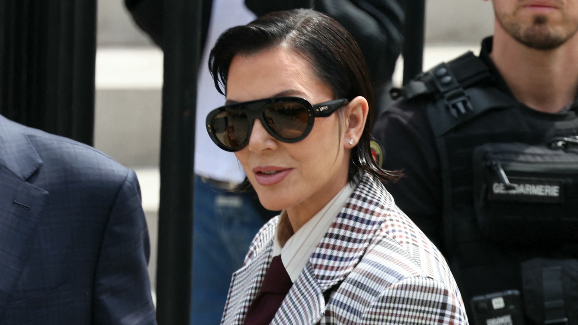 a woman with short dark hair wearing a printed suit in a paparazzi photo