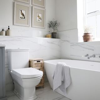 an en suite bathroom with a large bathtub and matching white WC and marble-look sourround