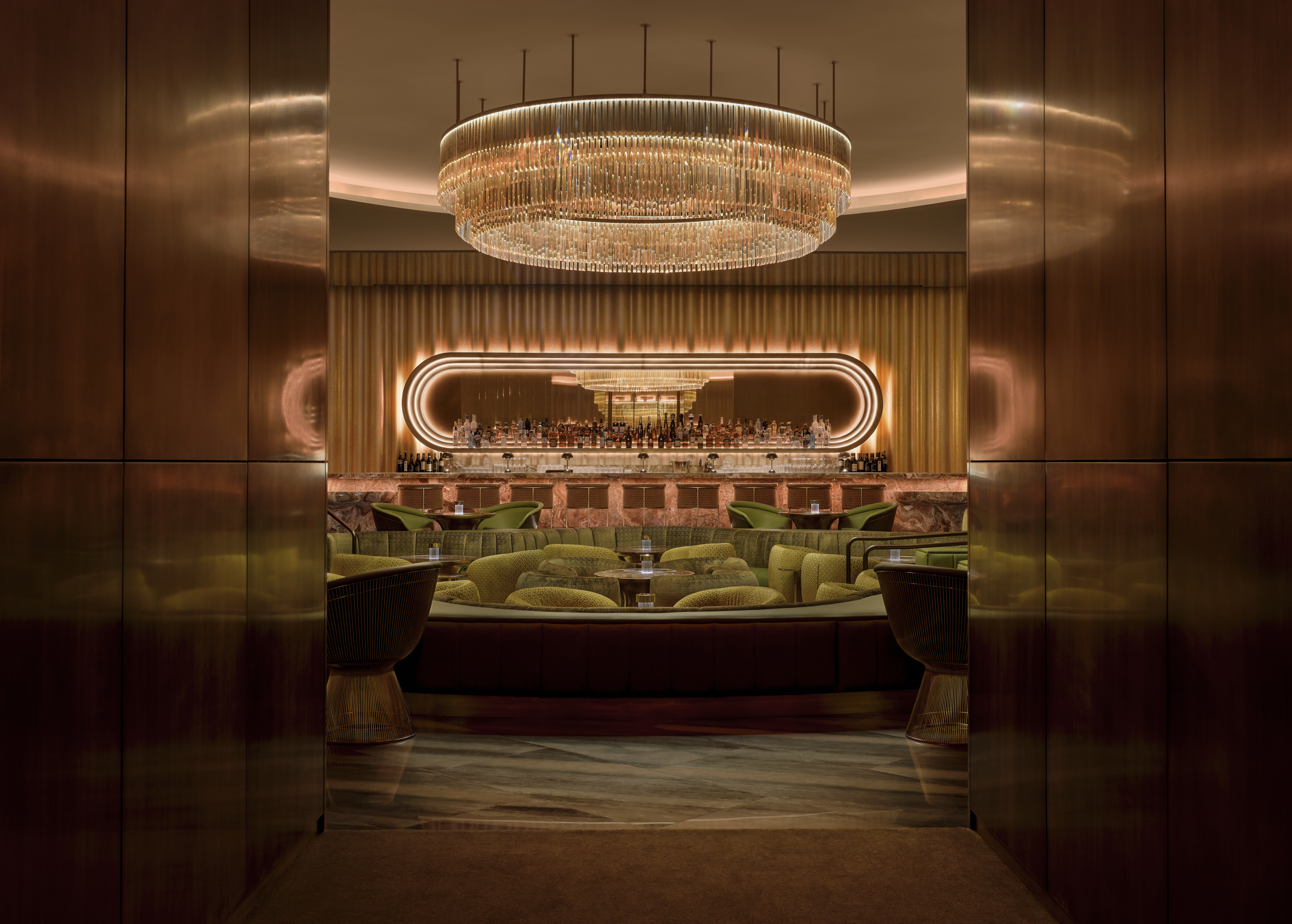 Green couches and a massive chandelier inside The Pinky Ring at Bellagio