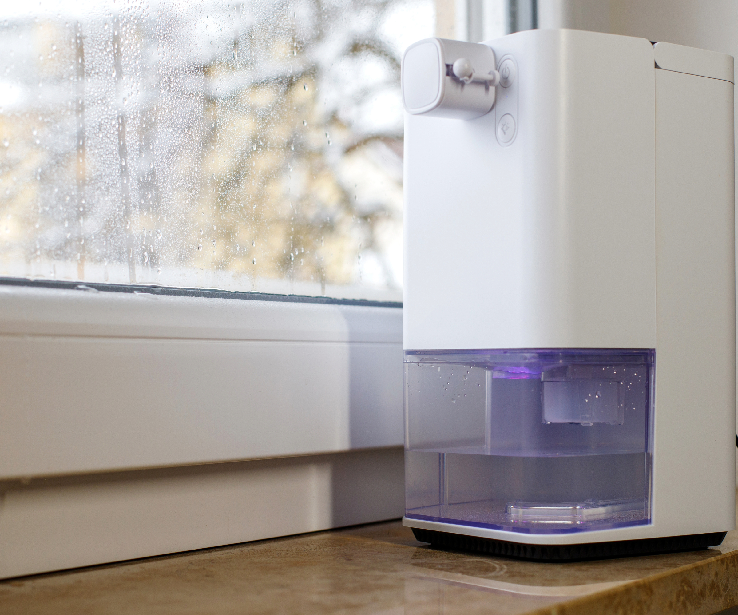 Dehumidifier placed on a windowsill next to a closed window