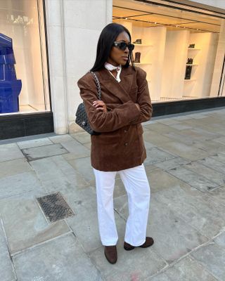 Woman in brown suede blazer, white jeans, and suede loafers