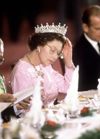 The Queen Adjusting Her Tiara Whilst Reading The Menu Before Dinner Is Served At A Banquet Held In Her Honour During Her Visit With Prince Philip To Peking, China