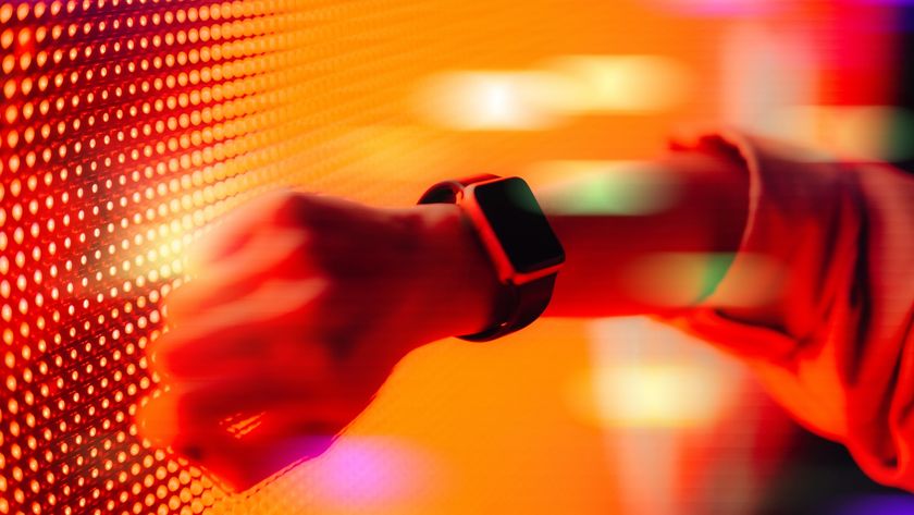 A photo of a person wearing a smartwatch with a colorful neon background