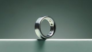The image shows a silver Oura Ring 4 against a sage green background