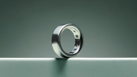 The image shows a silver Oura Ring 4 against a sage green background