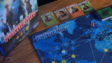 Pandemic board, cards, and tokens on a wooden table