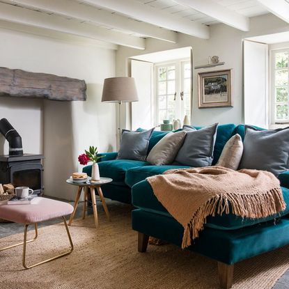 living room with white wall and bottle green colour sofa set and light brown colour floor mat