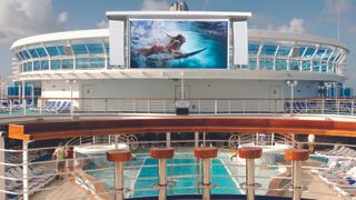 A cruise ship's deck on a sunny day with vivid imagery of a woman swimming on an LG dvLED display.