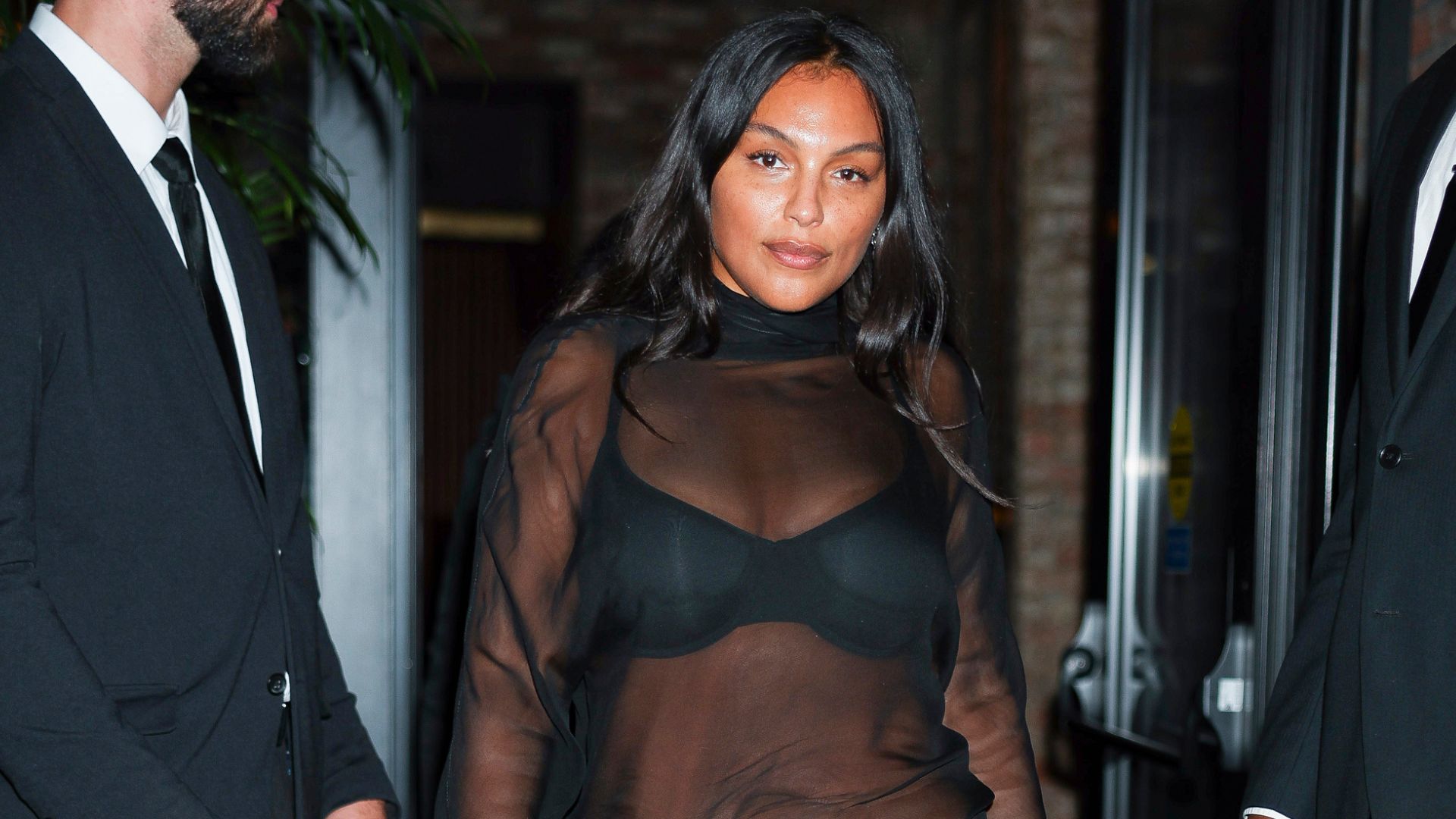 Paloma Elsesser wears a midiskirt with a sheer top and peep-toe shoes.