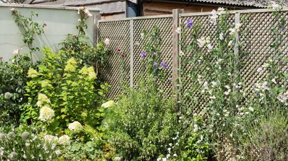 Outdoor seating area with corner sofa in front of cream painted fence