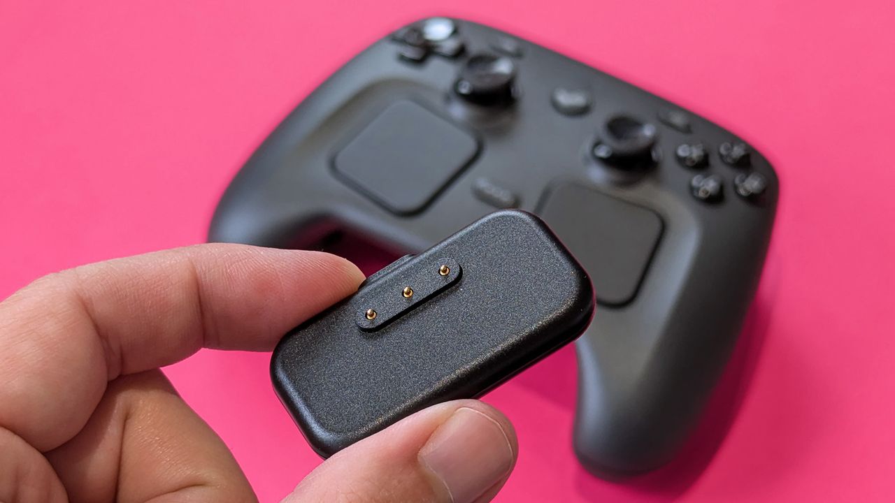 Charging puck for Valve Steam Controller (2026) held in hand against a magenta card
