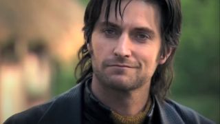 Richard Armitage smiles in the middle of a village in Robin Hood.