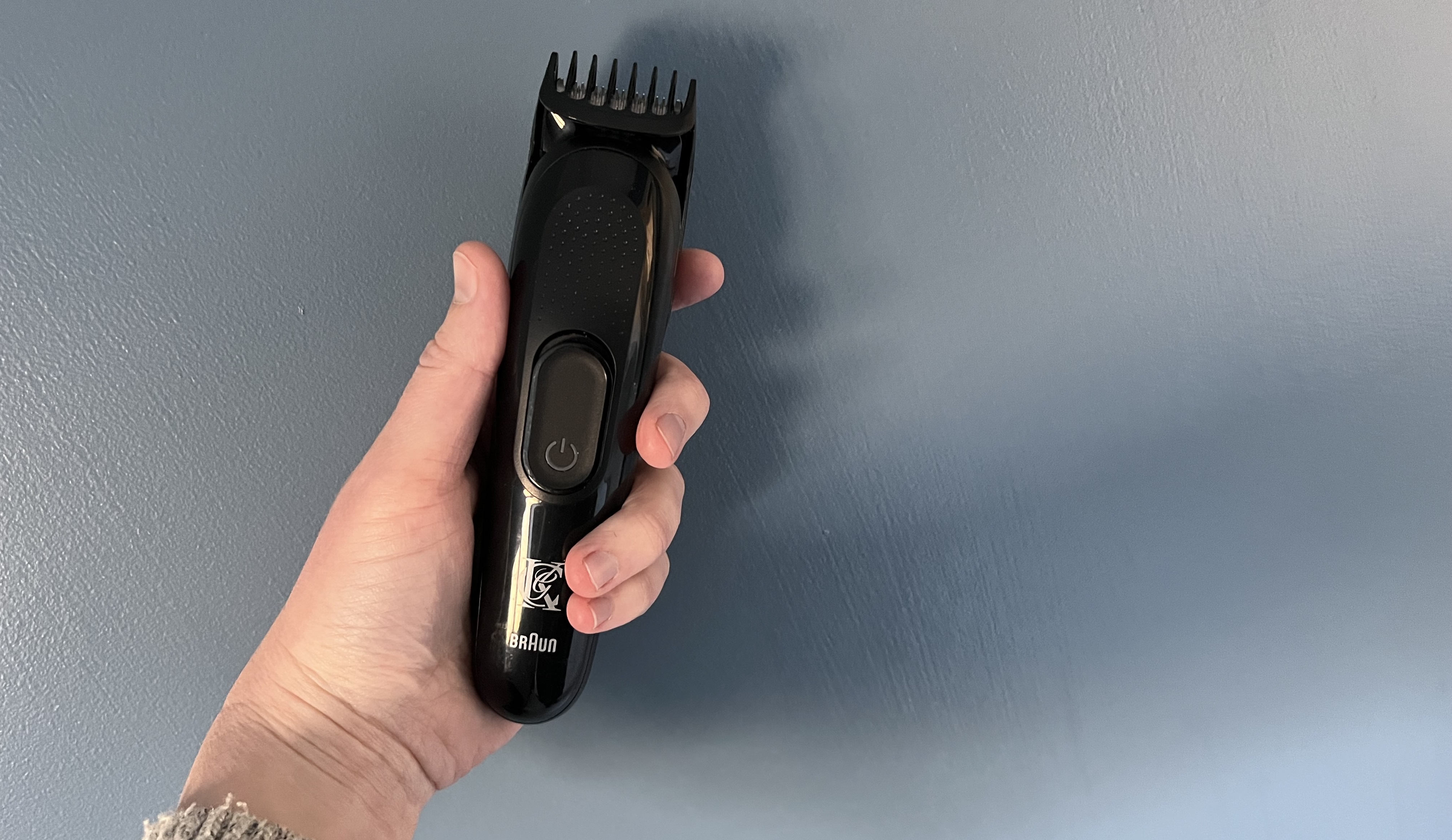 King C. Gillette Beard Trimmer in a hand in front of a wall
