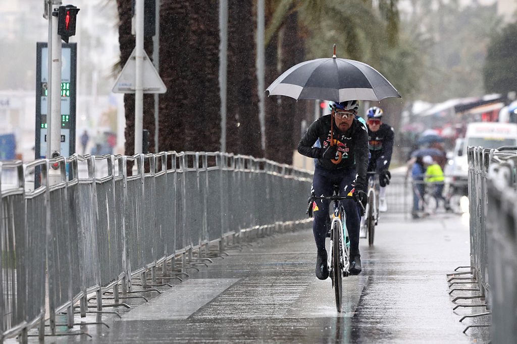 Red Bull - BORA - hansgrohe's Colombian rider Daniel Felipe Mart&iacute;nez, holding an umbrella, cycles to the start area of the 7th stage of the Paris-Nice cycling race, 120.4 km between Nice and Isola-Village, on March 14, 2026. (Photo by Anne-Christine POUJOULAT / AFP)