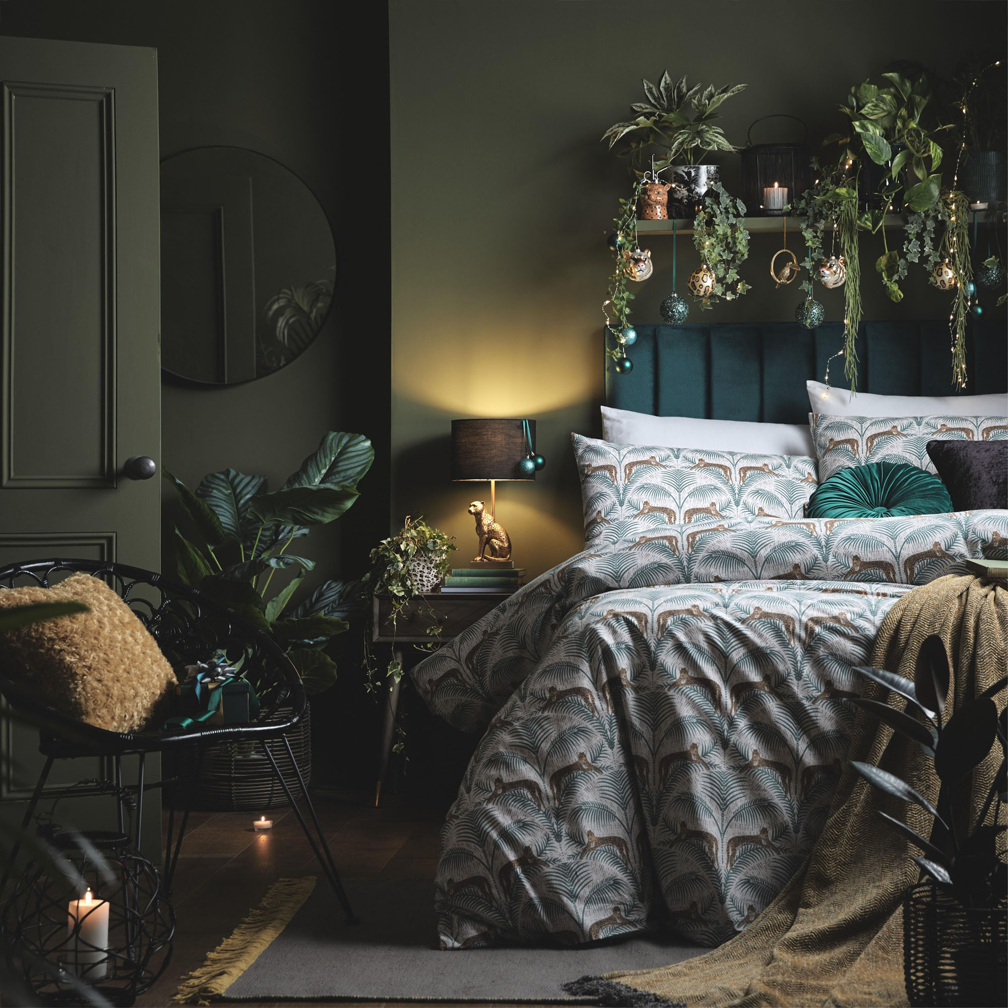 A bedroom with dark green wall paint decor, leopard print bedding and shelfie with baubles and plants