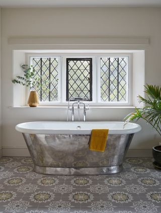 bathroom with silver bath, ornate tiles and leaded windows