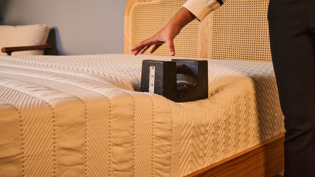 A tester places a weight on the right side of the Leesa Legend Hybrid Mattress to test its edge support.