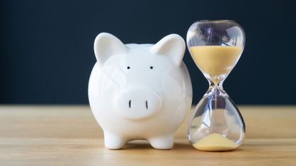 A piggy bank sits next to an hour glass.