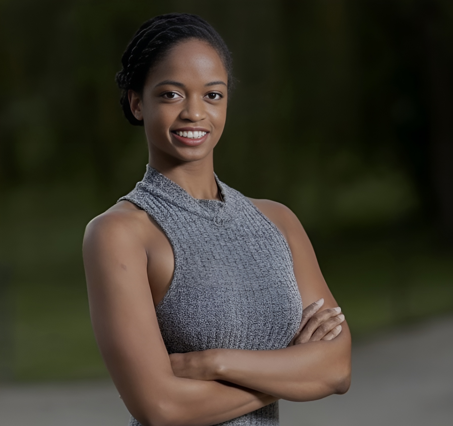 woman standing waist high facing the camera and smiling, wearing a grey sleeveless top