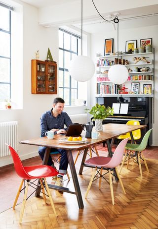 Carlo Viscione sitting at a table with Eames chairs in colourful shades