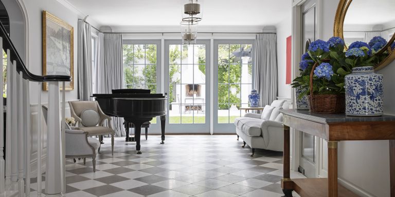 Entryway tile ideas with grey and white chequerboard floor, black piano, gold mirror and French windows to the garden
