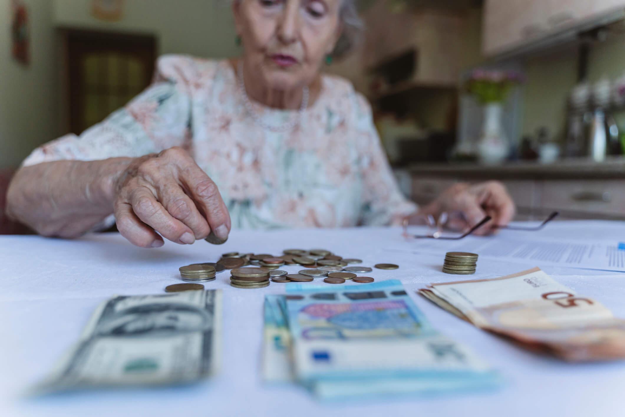  Senior woman counting coins on table at home 