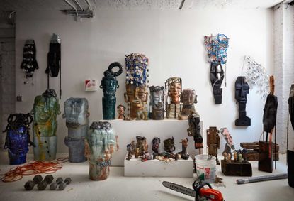 Leilah Babirye’s Brooklyn studio with wood and glazed ceramic sculptures and masks, many adorned with found objects, in varied states of completion.