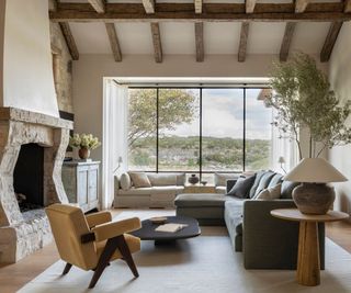 A living room with a neutral color scheme to enhance the relaxing energy. Plush soft furnishings have added, alongside greenery and beautiful views of nature