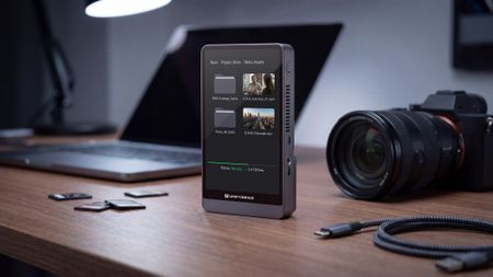 The UnifyDrive PixelMob sits on a desk with a laptop, camera, and SD cards