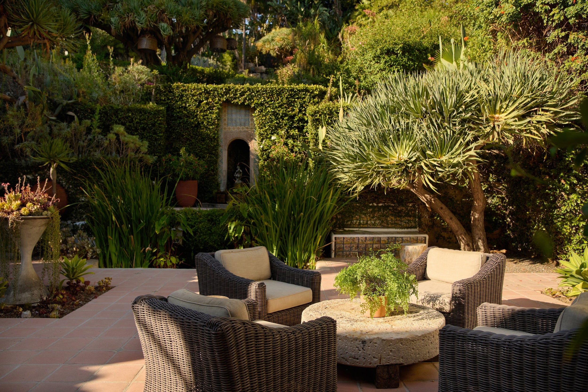 white and black outdoor seating surrounding a stone table in front of koi pond a various trees