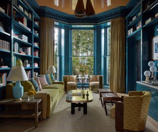 A blue and green library with floor-to-ceiling windows and a green couch