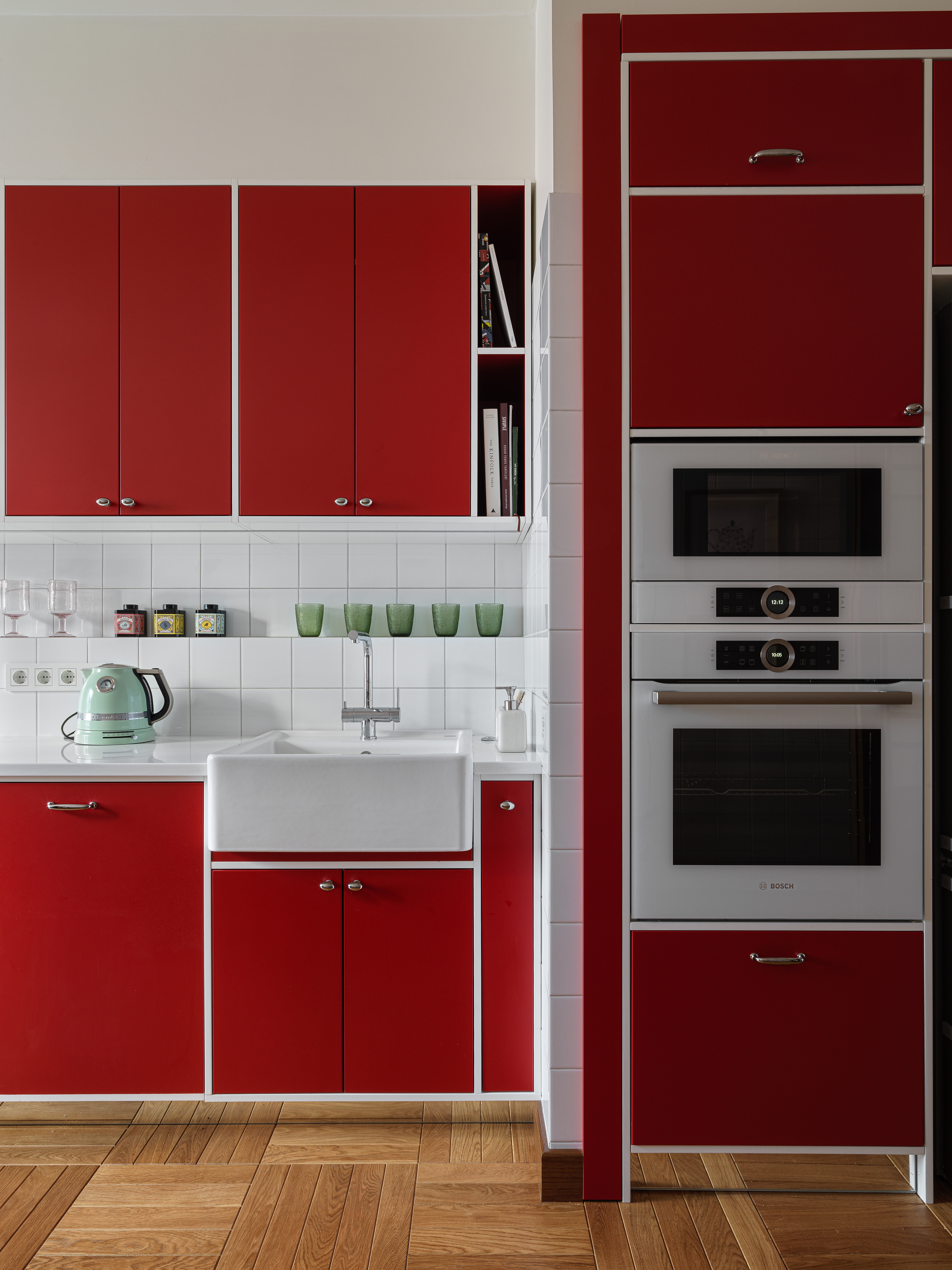 A kitchen with white backsplash and red cabinets