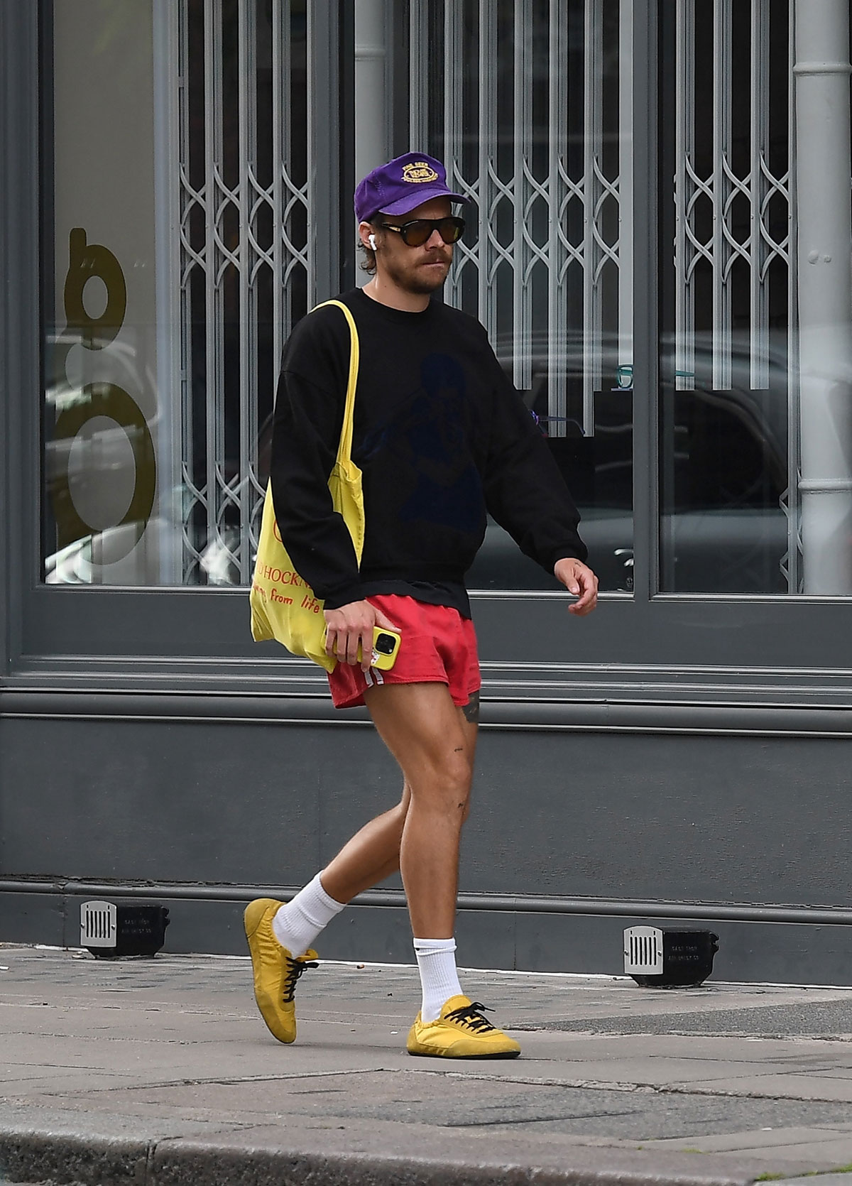 Harry Styles wearing red Adidas short shorts and yellow Prada sneakers.