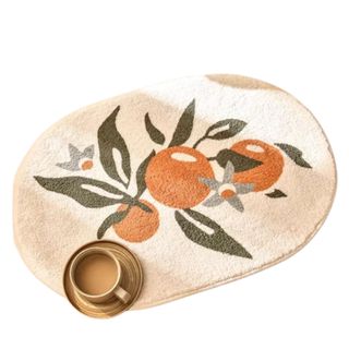 A white curved bath mat with oranges on it and a coffee cup