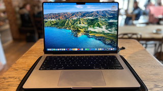 En Macbook Pro på 14 tum står öppnad på ett litet bord på ett café.