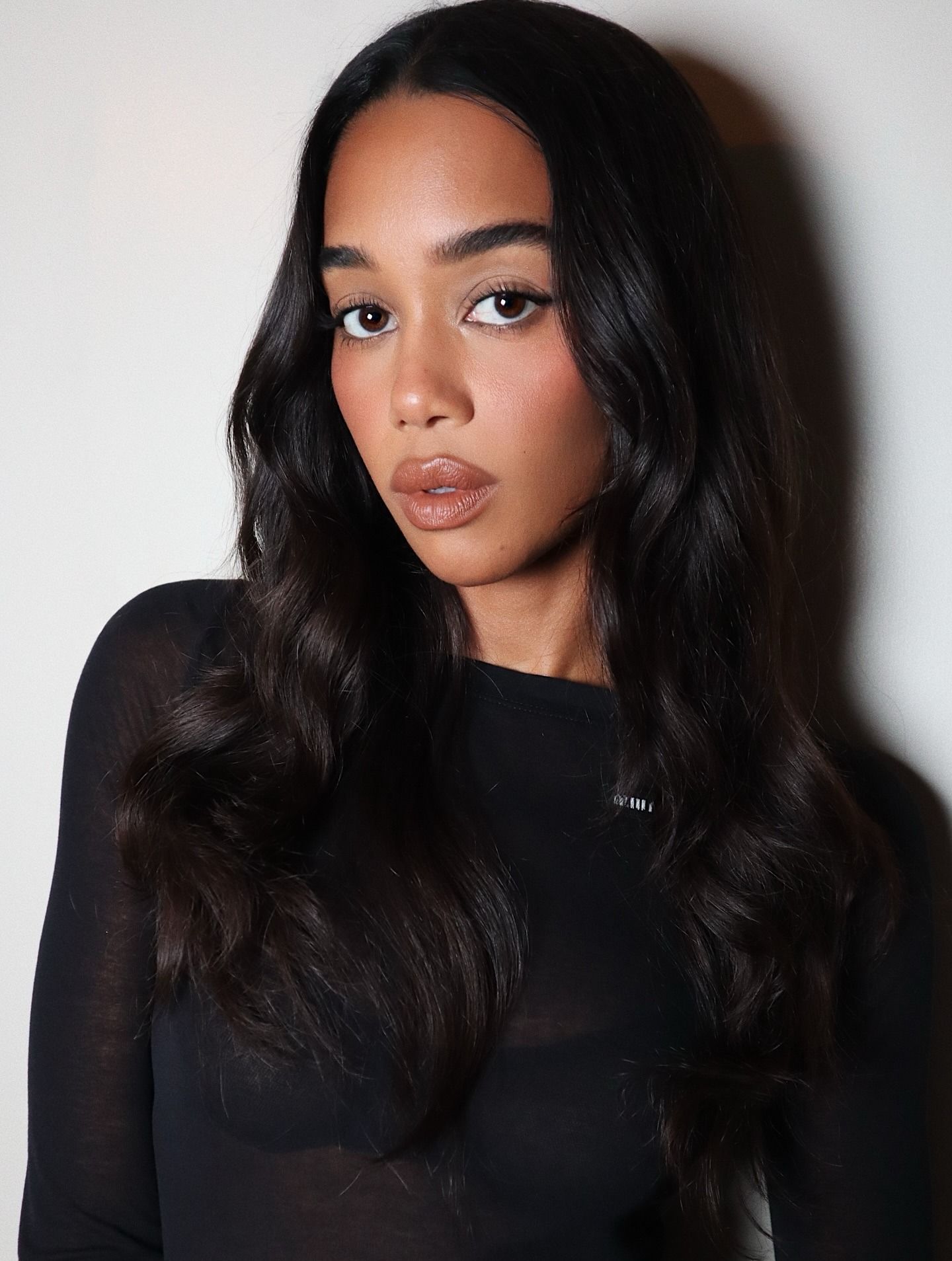 Laura Harrier with deep cool-toned brunette hair colour styled with loose waves