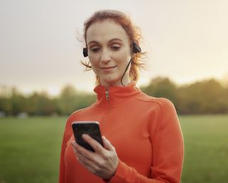 Woman jogging in park looking at phone