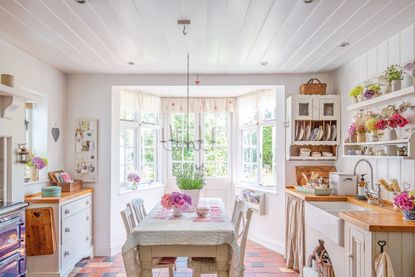 kitchen with painted furniture and red quarry tiles patchwork quilt on table