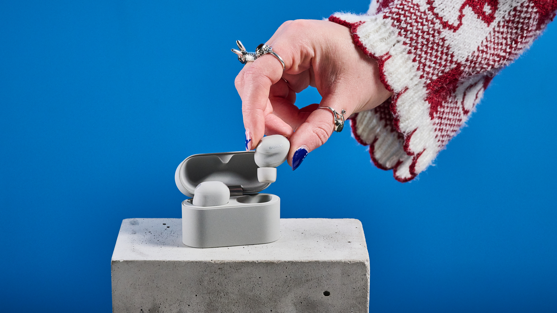 Sony WF-1000XM6 earbuds photographed in front of a blue background