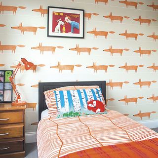 bedroom with foxes wallpaper and black frame with orange lamp on bedside table